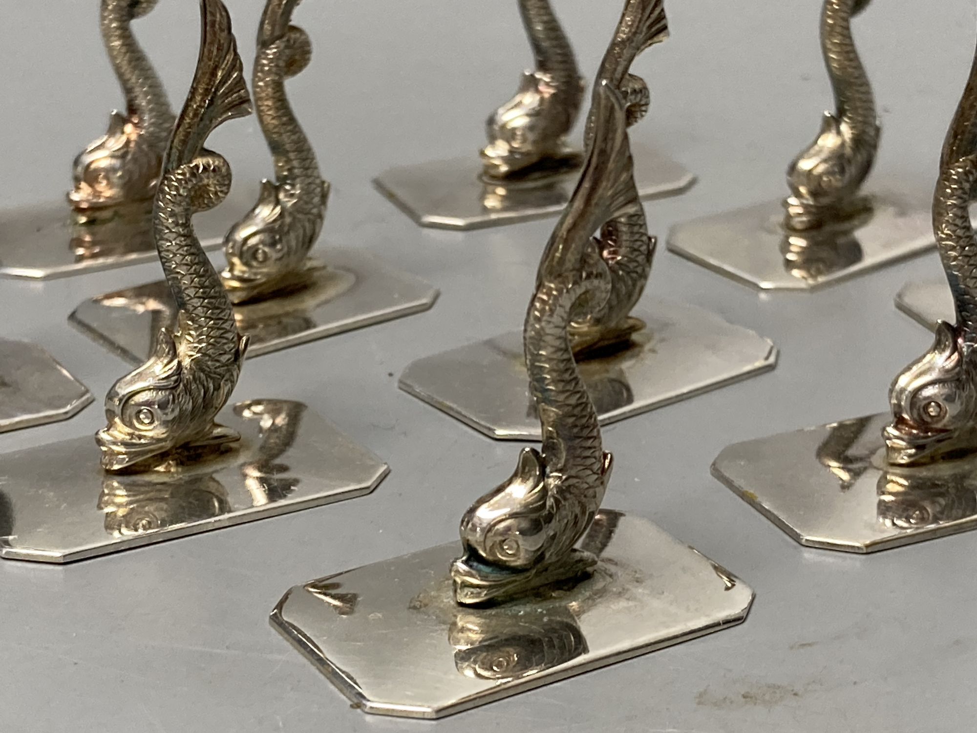 A set of twelve Portugese silver dolphin place/menu holders, height 4cm